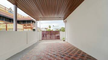 A covered outdoor area with a tiled floor, a gate, and a building in the background.