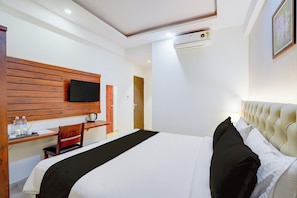 A hotel room with a bed, a desk, a chair, a television mounted on the wall, and an air conditioning unit. - Palette Hotel and Resort Manyata Tech (Bengaluru)