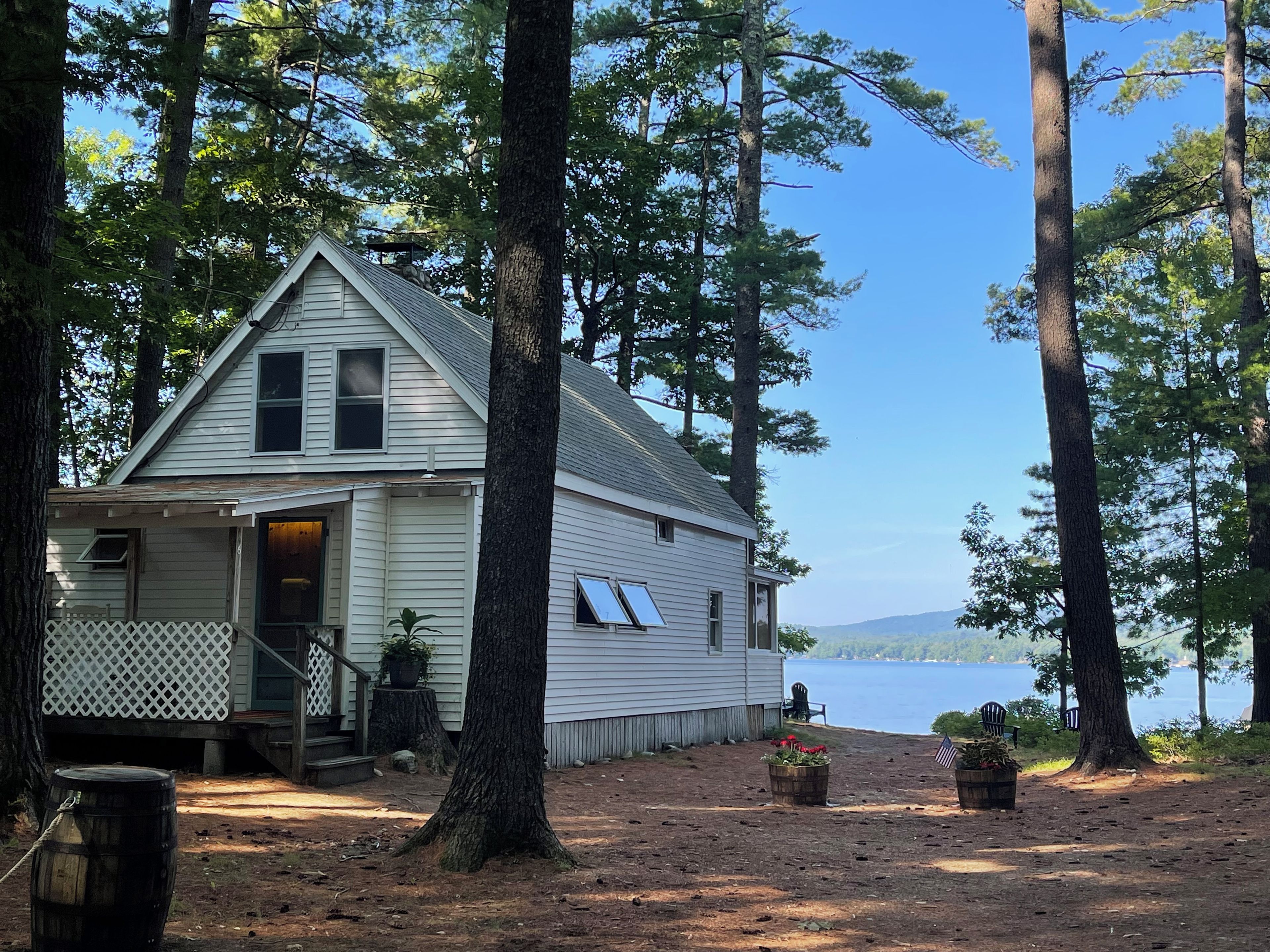 A cabin with a porch, a small deck, and a view of a lake.