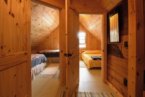 Ein Holzinterieur mit zwei Betten, einer Tür und einem Fenster.