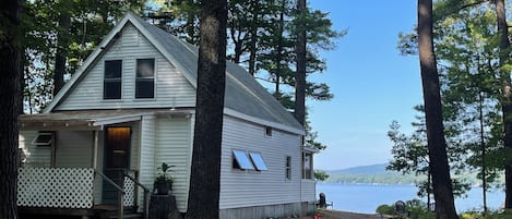 A cabin with a porch, a small deck, and a view of a lake.