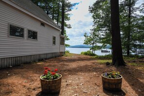 Ett hus med en grusgång som leder till en sjö, omgivet av träd.