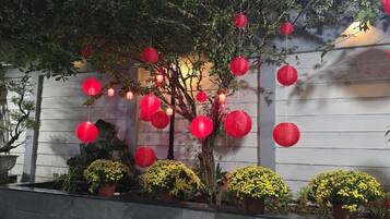 Un jardín con plantas en macetas y faroles rojos.