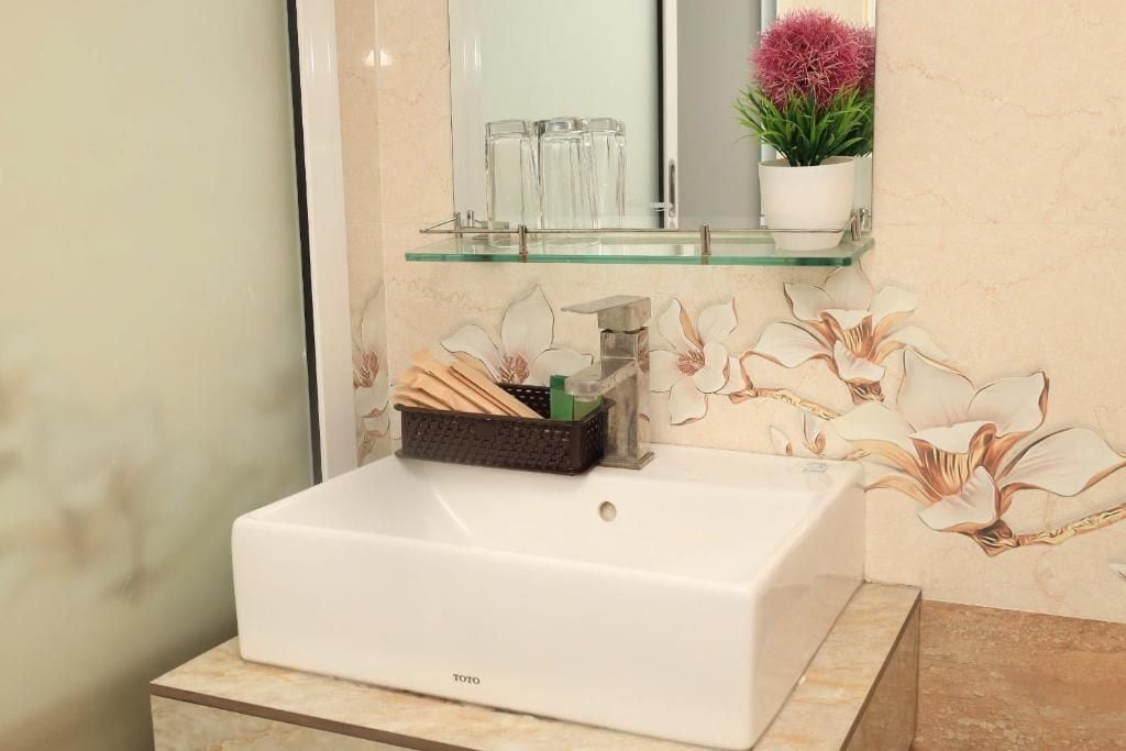A bathroom with a white sink, a glass shelf above it, and a floral wall design.