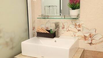 A bathroom with a white sink, a glass shelf above it, and a floral wall design.