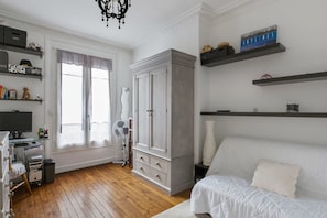 A bedroom with a bed, a wardrobe, a desk with a computer, and a window with curtains. - A TRUE PARISIAN TREAT WITH PVT BALCONY & CAFE'S ALL AROUND (Paris)