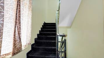 A staircase with a handrail and a window with patterned curtains.