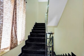 A staircase with a handrail and a window with patterned curtains. - Collection O Utsav Grand RR Nagar (Bangalore)