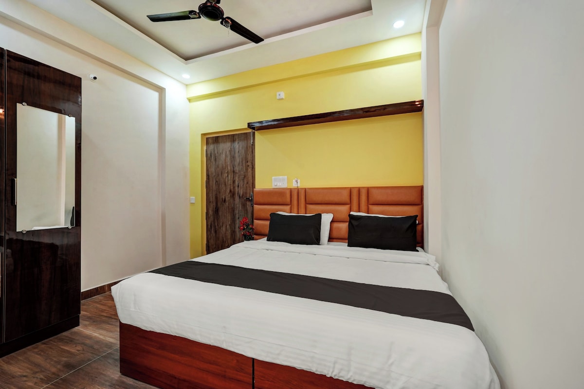 A bedroom with a bed, a ceiling fan, and a wooden wardrobe.