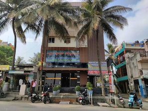A hotel with a modern facade, multiple balconies, and a signboard advertising hotel services. - Collection O Utsav Grand RR Nagar (Bangalore)