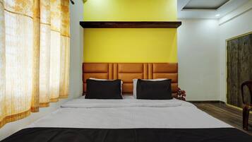 A hotel room with a large bed, a wooden headboard, and a yellow accent wall.