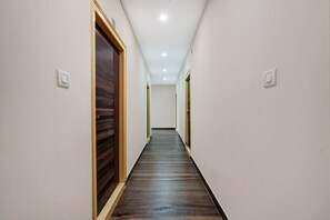 A narrow hallway with wooden flooring and white walls. - Collection O Utsav Grand RR Nagar (Bangalore)