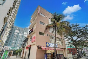 Un edificio de varios pisos con un letrero que anuncia 'SV DELITE CAFE' ofreciendo pizza, comida china y sándwiches.