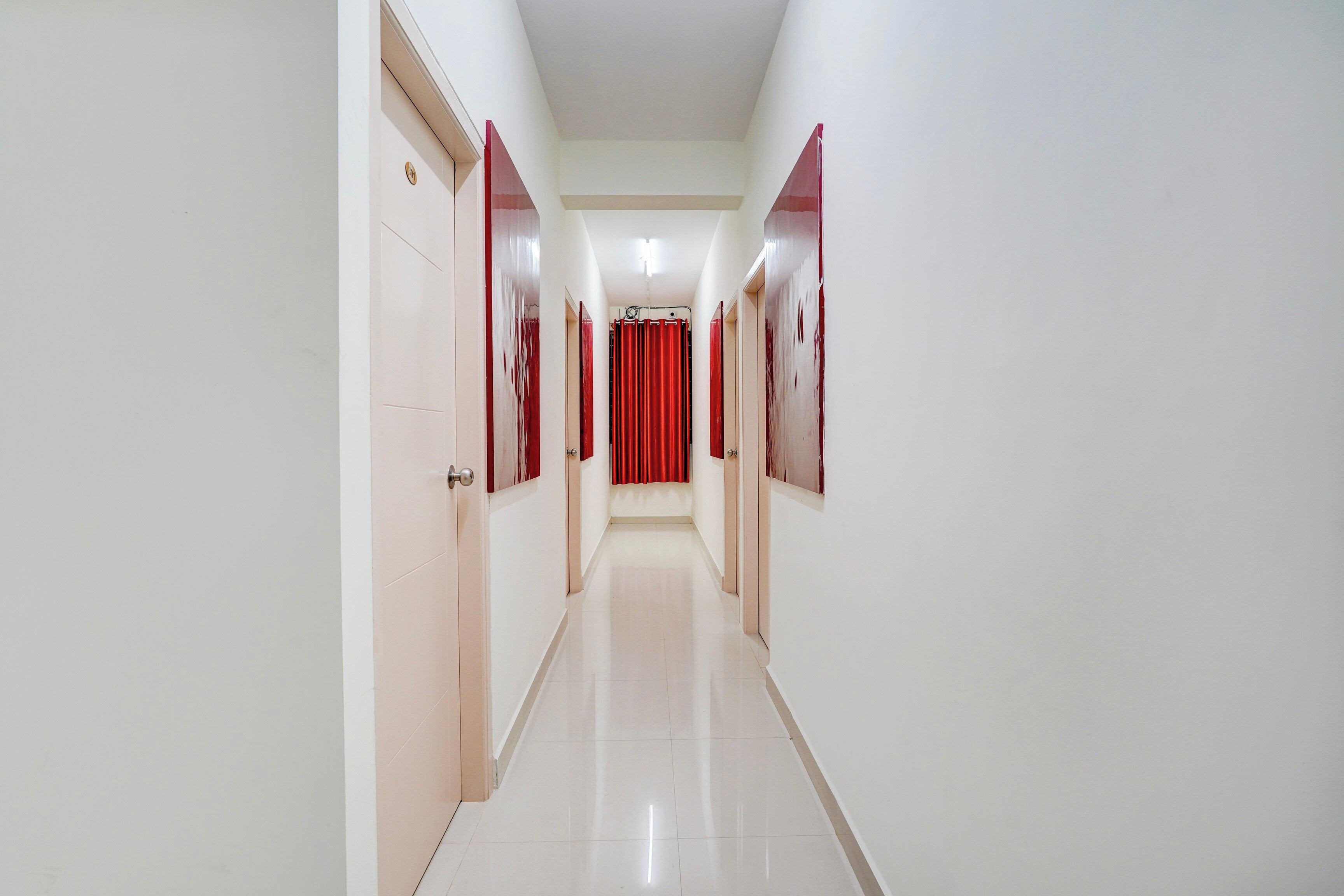 A long, narrow hallway with white walls and doors on either side.