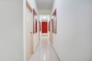Un pasillo largo y estrecho con paredes blancas y puertas a ambos lados.