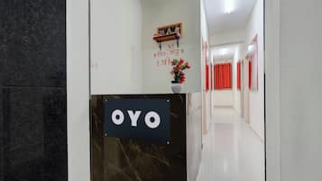 A reception area with a marble reception desk labeled 'OYO' and a wall with a religious painting and text.