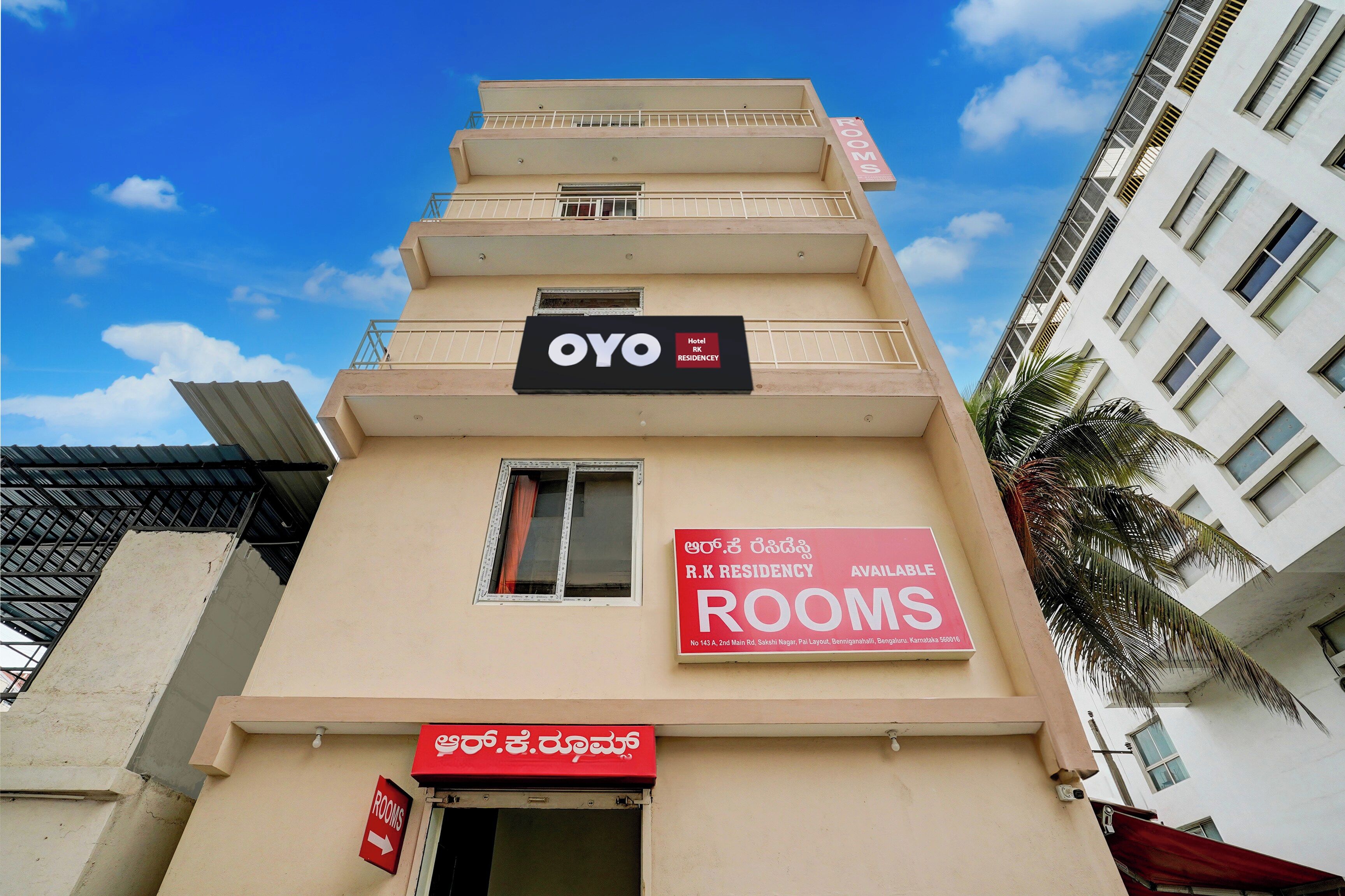 A hotel building with multiple floors, a sign indicating rooms are available, and a sign for R.K Residency.