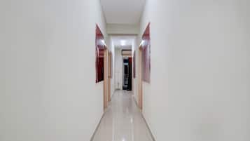 Un pasillo largo y estrecho con paredes blancas y un piso de baldosas brillantes.
