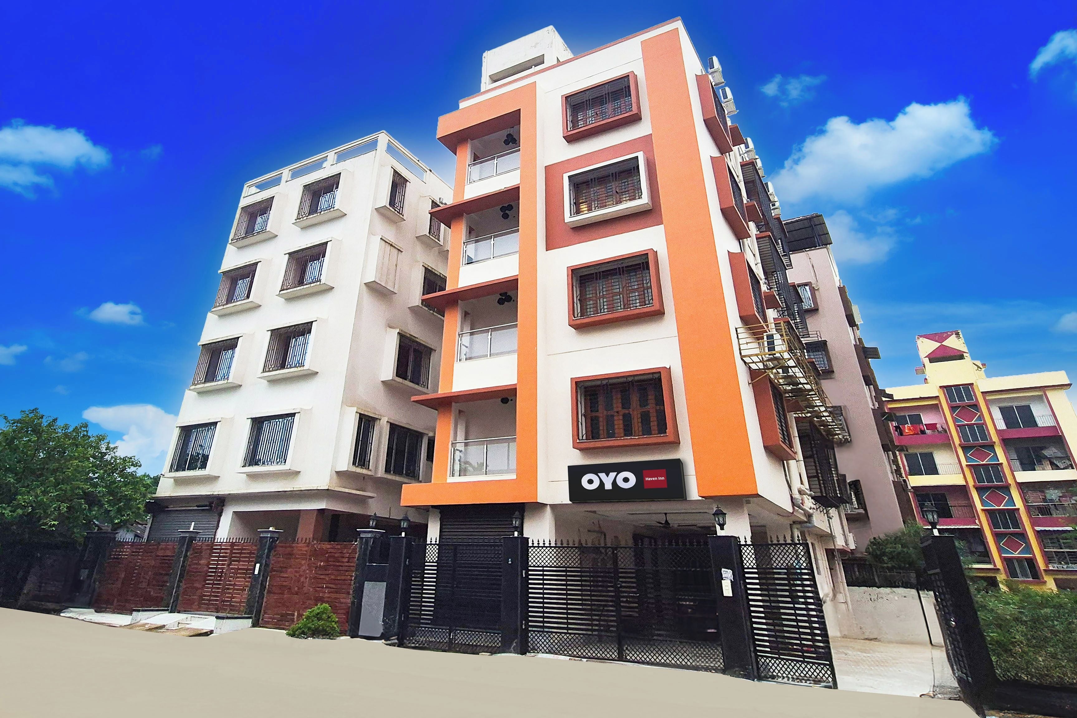 Un hotel de varios pisos con un llamativo letrero 'OYO Haven Inn', con balcones y una entrada protegida por una reja.