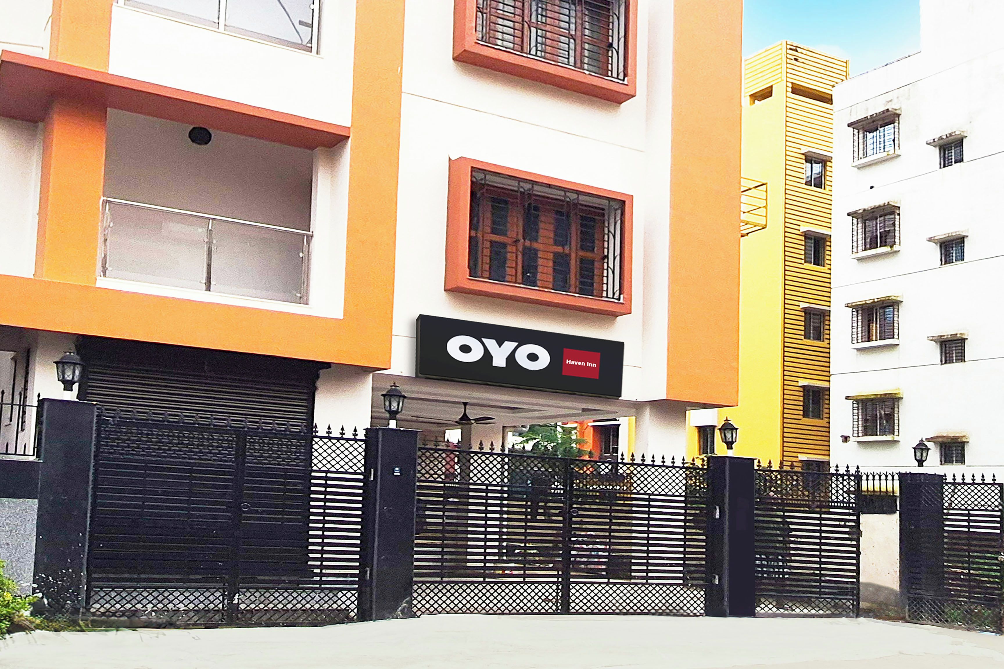 Un hotel con fachada negra y naranja, entrada protegida por una reja y un cartel que dice 'OYO Haven Inn'.