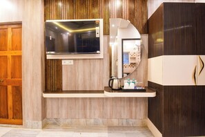 Un baño moderno con televisor integrado, espejo y cafetera sobre una encimera.