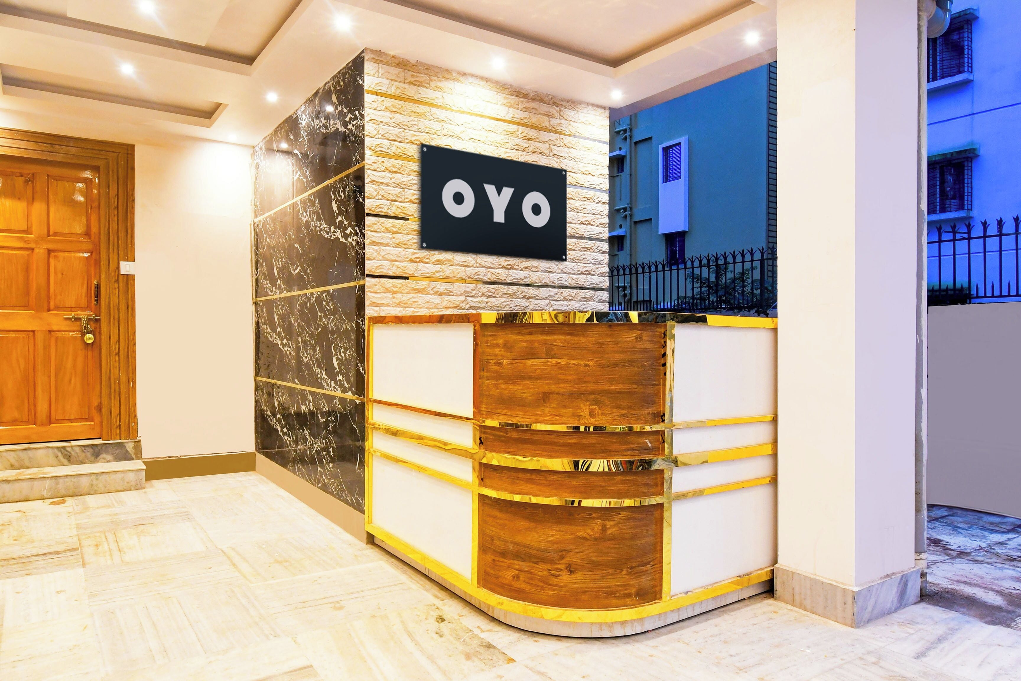 Una mesa de recepción con un letrero que dice 'OYO' y una pared de textura de piedra al fondo.