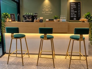 A coffee shop counter with a menu board, three bar stools, and a coffee machine. - The Temple Phuket (Chang Wat Phuket)