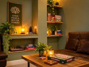A cozy living room with a wooden coffee table, board games, and a framed inspirational quote on the wall. - The Temple Phuket (Chang Wat Phuket)