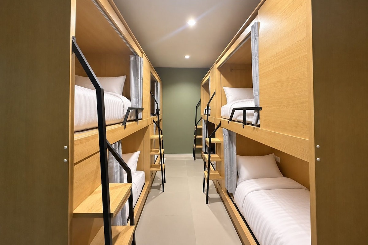 A corridor with bunk beds, wooden railings, and a tiled floor.