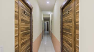 A corridor with wooden doors, white walls, and a tiled floor.
