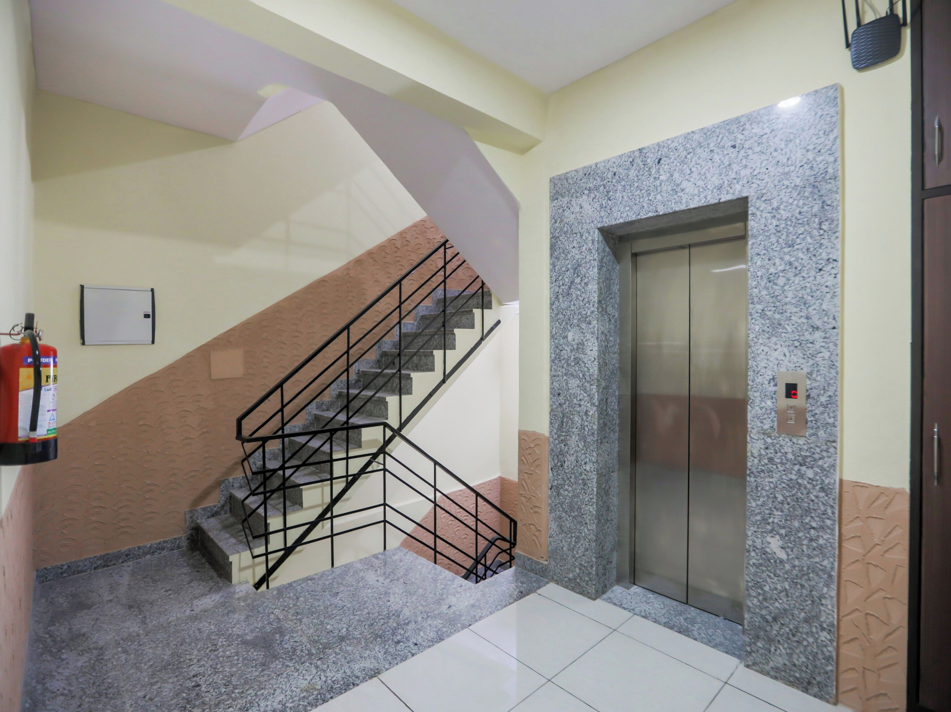 A staircase with a metal railing, an elevator, and a fire extinguisher on the wall.