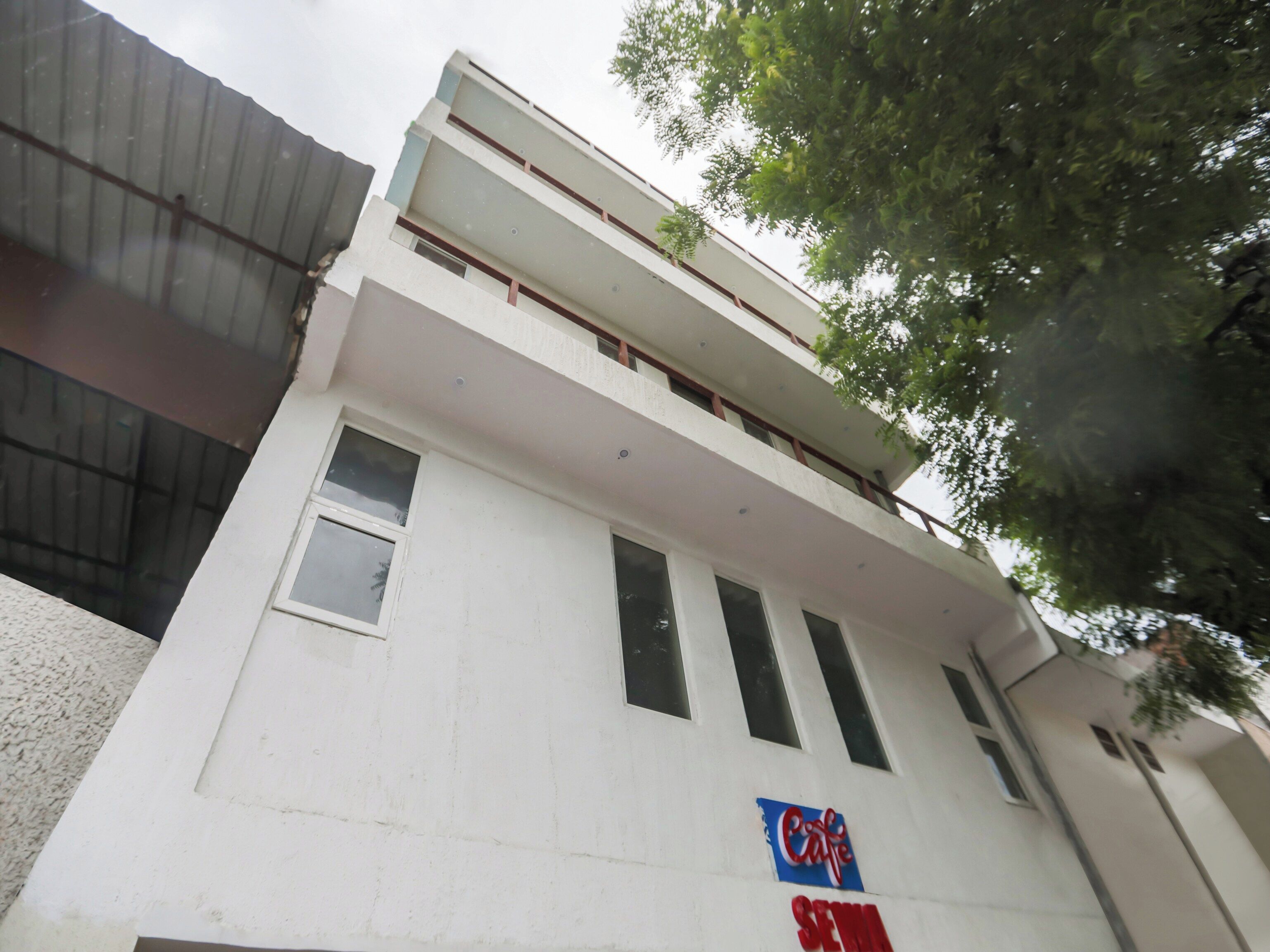 Un edificio con fachada blanca, múltiples ventanas y un letrero que dice 'Cafe'.