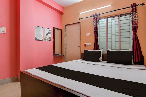A room with a bed, a window with curtains, a wall-mounted mirror, and a small shelf with a decorative item. - Hotel O Santoshpur Lakeview (Kolkata)