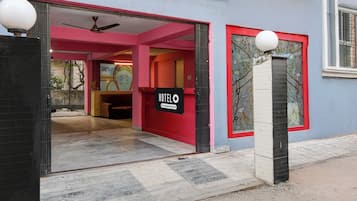 Ein Hotel mit roter und blauer Fassade, einem Schild, das es als betriebseigener Hotel kennzeichnet, und einem gefliesten Eingangsbereich.