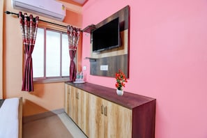 A room with a wooden cabinet, a flat-screen TV mounted on the wall, and a window with curtains. - Hotel O Santoshpur Lakeview (Kolkata)