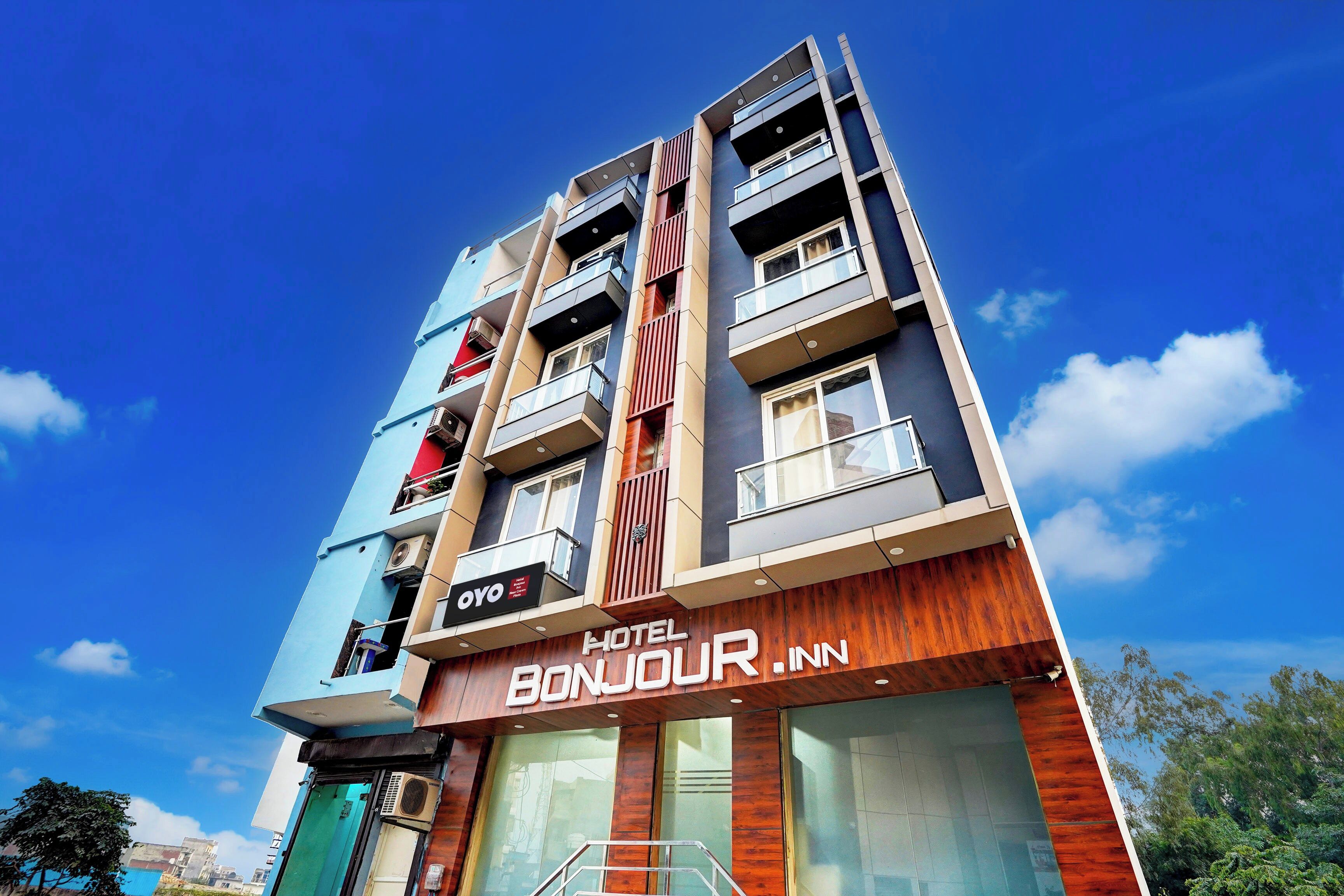 A multi-story hotel with balconies, a sign indicating it is a hotel, and a clear blue sky in the background.