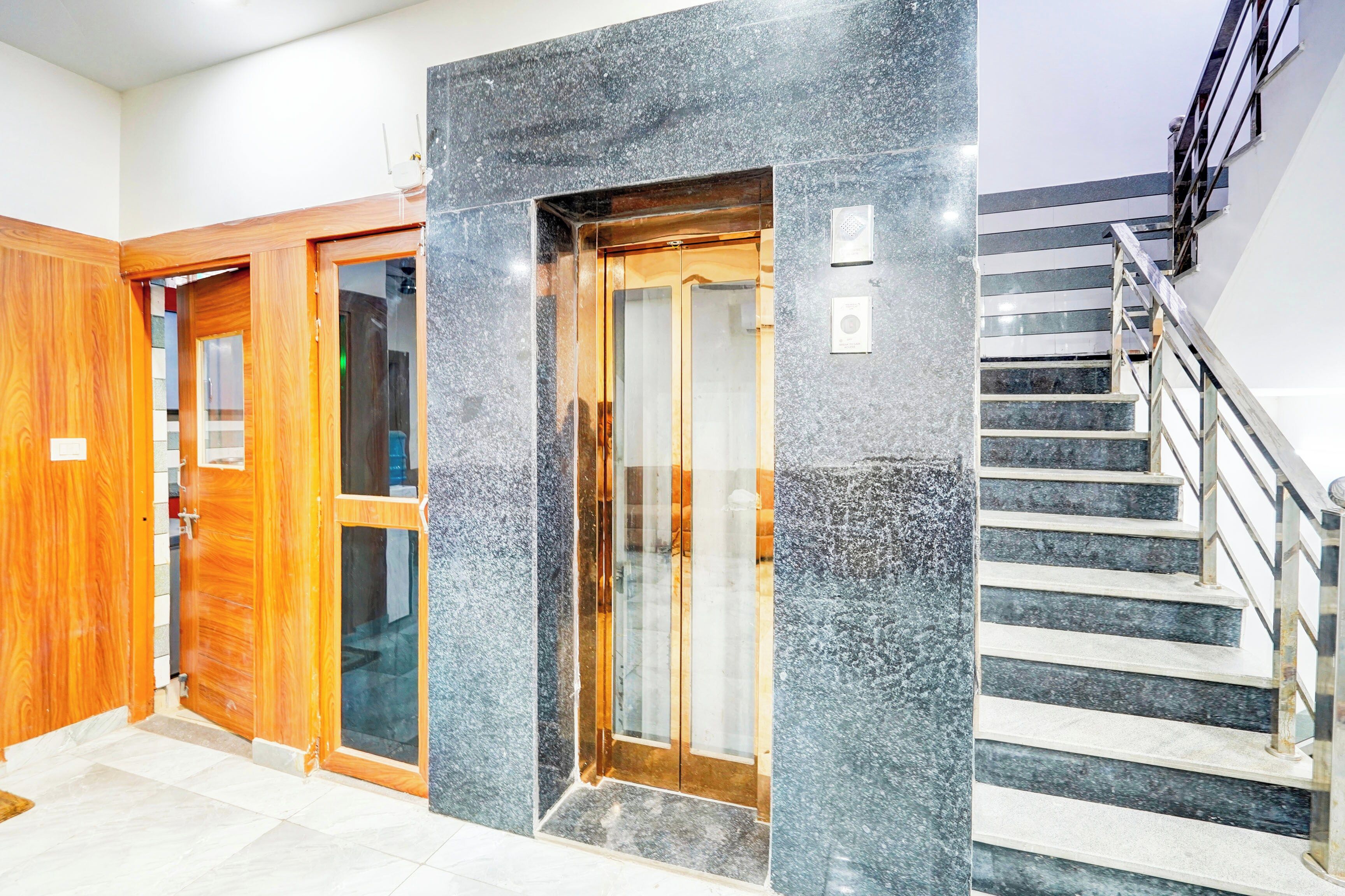 A hotel entrance with a wooden door, a glass door, and a staircase with metal railings.