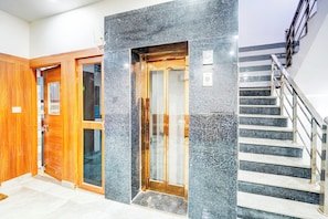 A hotel entrance with a wooden door, a glass door, and a staircase with metal railings.