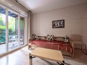 A modern bedroom with a wooden bed, a small table, and a sliding glass door leading to an outdoor area. - Apartment with a terrace and an outdoor pool (Ax-les-Thermes)