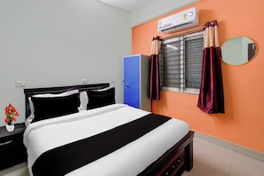 Habitació d'hotel amb un llit, un armari, un aparell d'aire condicionat, una finestra amb cortines i un mirall a la paret.