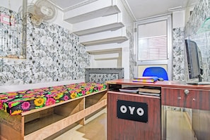 A room with a bed, a desk with a computer, a chair, and a wall with floral wallpaper. - Hotel O New Cuttack Guest House (Cuttack)