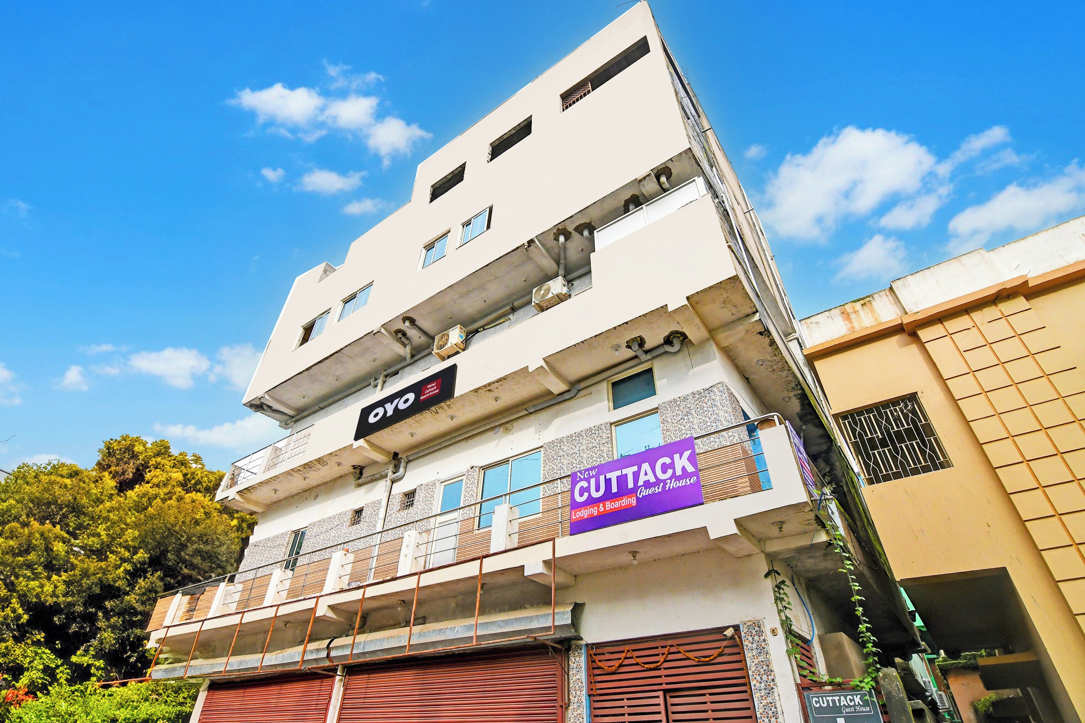 A multi-story building with a sign for 'New Cuttack Guest House' indicating lodging and boarding services.