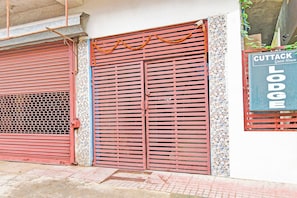 A building with two red metal shutters, a signboard for 'Cuttack Guest House Lodge', and a decorative garland. - Hotel O New Cuttack Guest House (Cuttack)