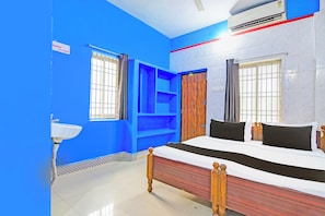A room with a bed, a window, a sink, and a blue wall. - Hotel O New Cuttack Guest House (Cuttack)