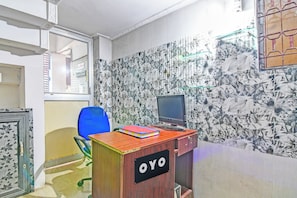 A room with a desk, a chair, a computer, and a wall with a floral pattern. - Hotel O New Cuttack Guest House (Cuttack)