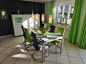 A modern dining area with a table, chairs, and a window with curtains. - Holiday Home in Nieblum With Swimming Pool (Nieblum)