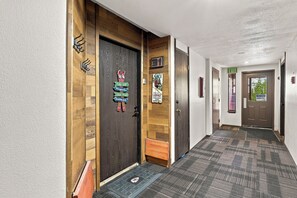 Passadís d'hotel amb portes de fusta, un terra amb moqueta i un senyal que indica una sortida.