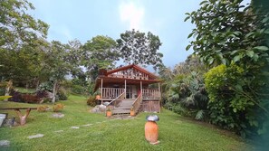 A wooden house with a porch, surrounded by lush greenery and a clear sky. - LA CABAÑA EN The GUADUAL (San Antonio Del Tequendama)