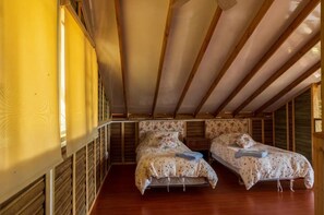 A bedroom with two beds, wooden beams on the ceiling, and a window on the left. - LA CABAÑA EN The GUADUAL (San Antonio Del Tequendama)