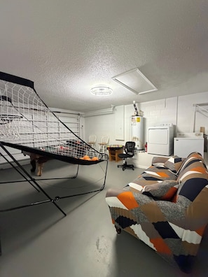 A room with a basketball hoop, a sofa, a heater, and a washing machine. - Cozy Home minutes from Disney (Davenport)